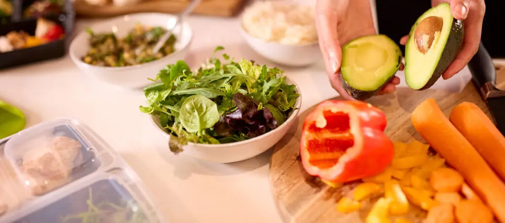 Employees preparing healthy lunches in an office kitchen, encouraging workplace wellness