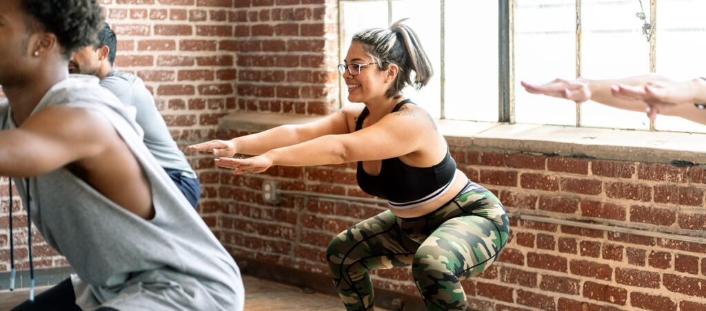 Young lady doing bodyweight squats to lose weight in gym while taking GLP-1 medications like Ozempic, Wegovy, and Mounjaro.