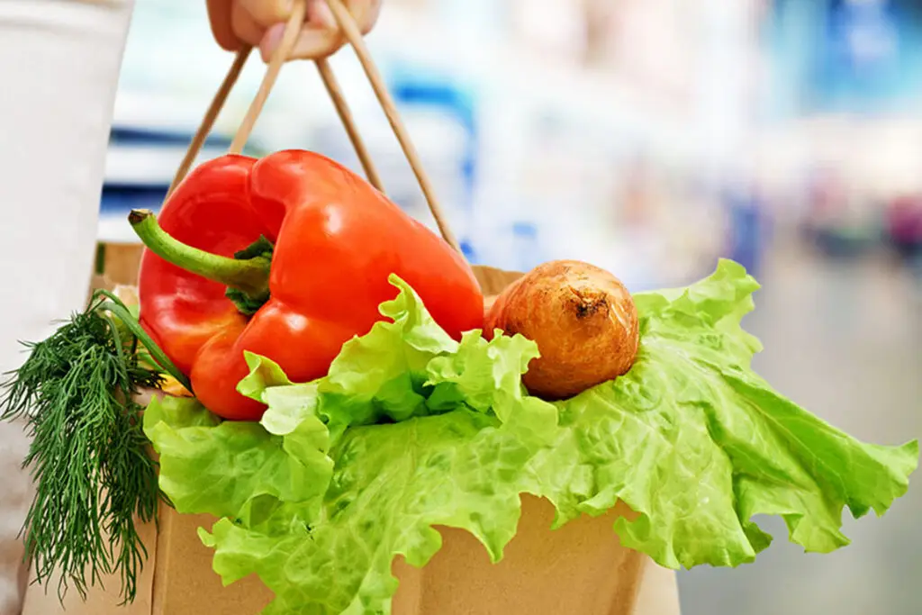 A guide to grocery shopping for GLP-1 medical weight loss patients, hand carrying fresh produce in bag