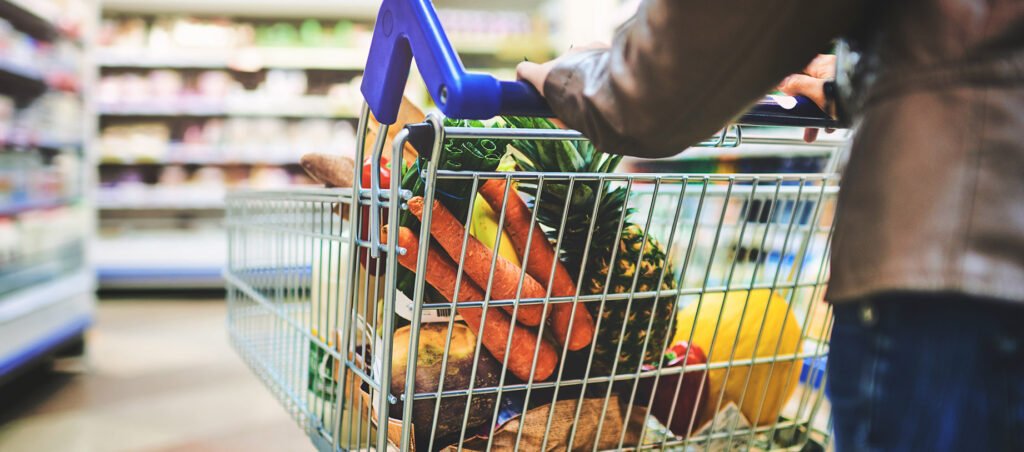 Lady pushing shopping cart through grocery store, how to shop for food while taking GLP-1 weight loss drugs like Ozempic