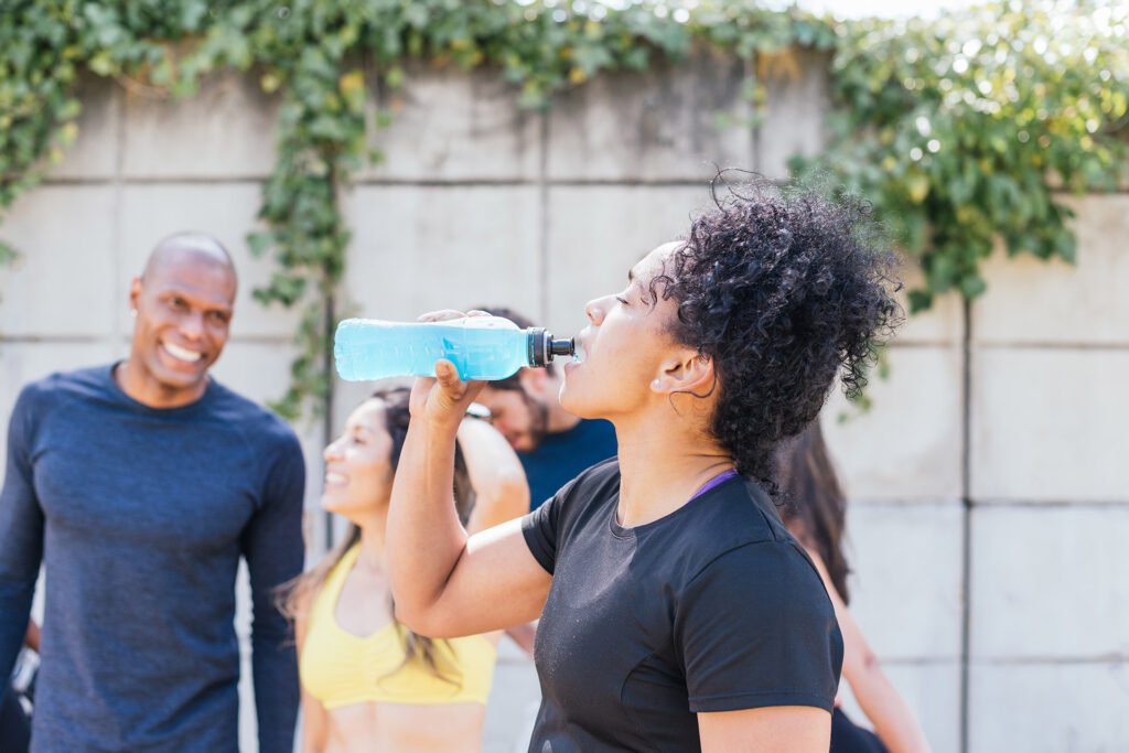 Lady drinking water bottle during exercise for hydration as part of GLP-1 medical weight loss plan with Ozempic