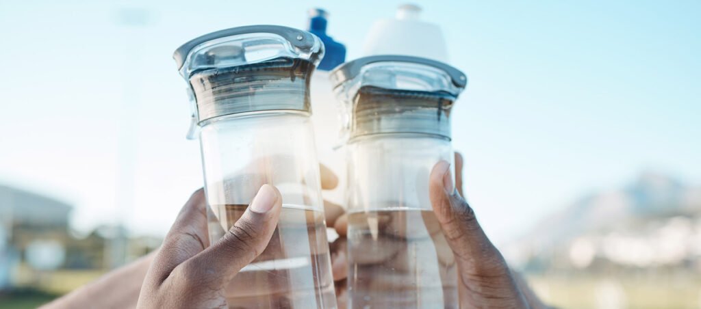 Friends lifting water bottles in the air as an example of hydration to promote weight loss and exercise activities