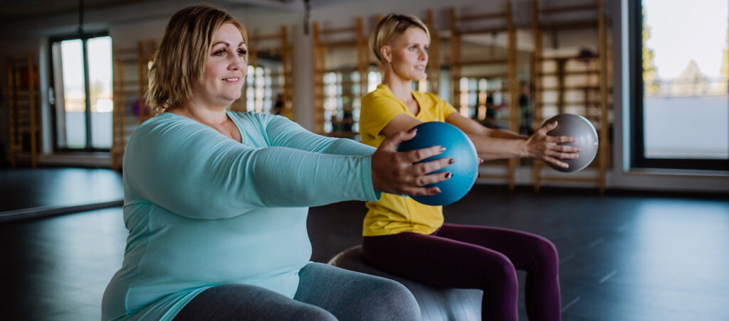 Lady with personal trainer doing muscle building, strength training exercise to lose weight and tone muscle as part of GLP-1 weight loss plan