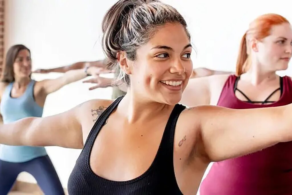 A woman smiles while stretching in yoga class.