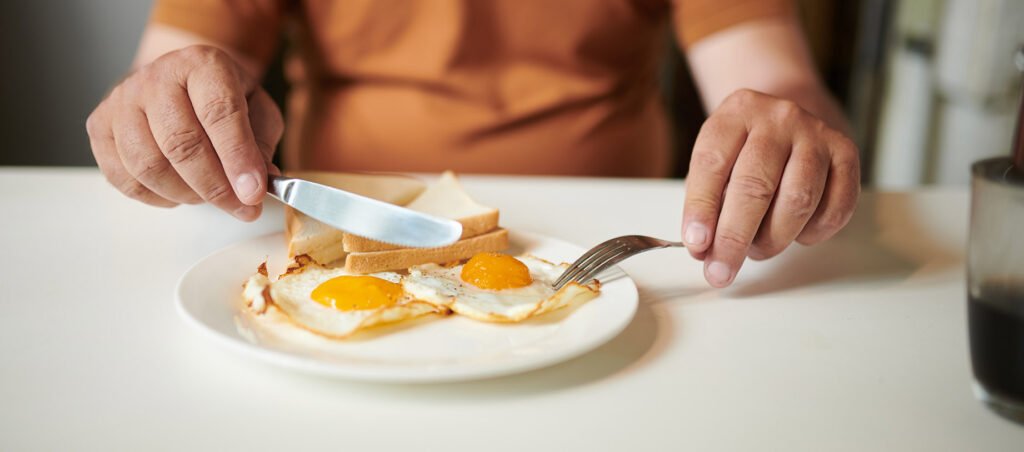 Man eating eggs for breakfast to incorporate high protein into diet for weight loss with medications.