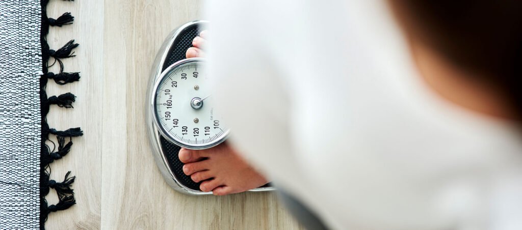 Woman standing on bathroom scale to check progress along her GLP-1 medical weight loss journey with prescription Victoza