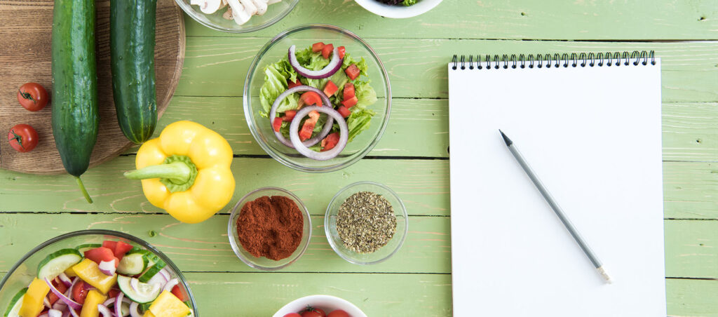 Weekly meal plan on wooden table next to examples of high-protein, fiber-rich foods to promote weight loss and muscle building while taking weight loss medications like Ozempic, Wegovy, Mounjaro, and Zepbound