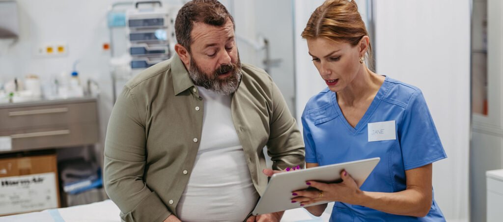 Male patient taking Mounjaro prescription weight loss drug speaks with medical provider at a routine visit for obesity treatment