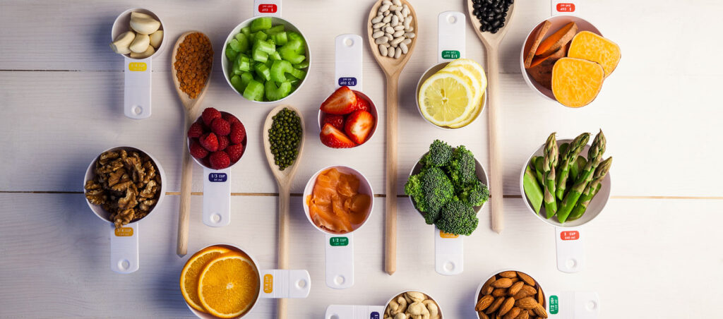 Table with measuring cups of healthy, nutritious food illustrating the importance of a balanced diet while on a medical weight loss journey