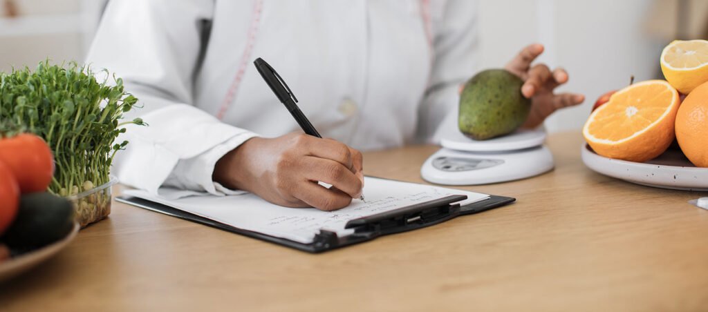 Registered Dietitian Nutritionist weighs mango on food scale as she prepares a meal plan for a GLP-1 medical weight loss patient