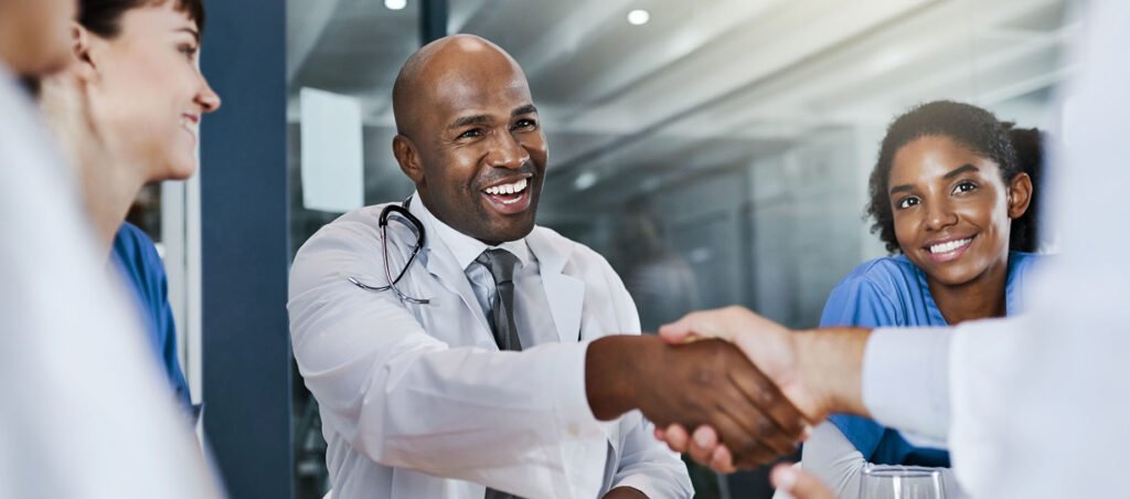 Medical providers shake hands after agreeing on referral partnership to improve holistic patient care