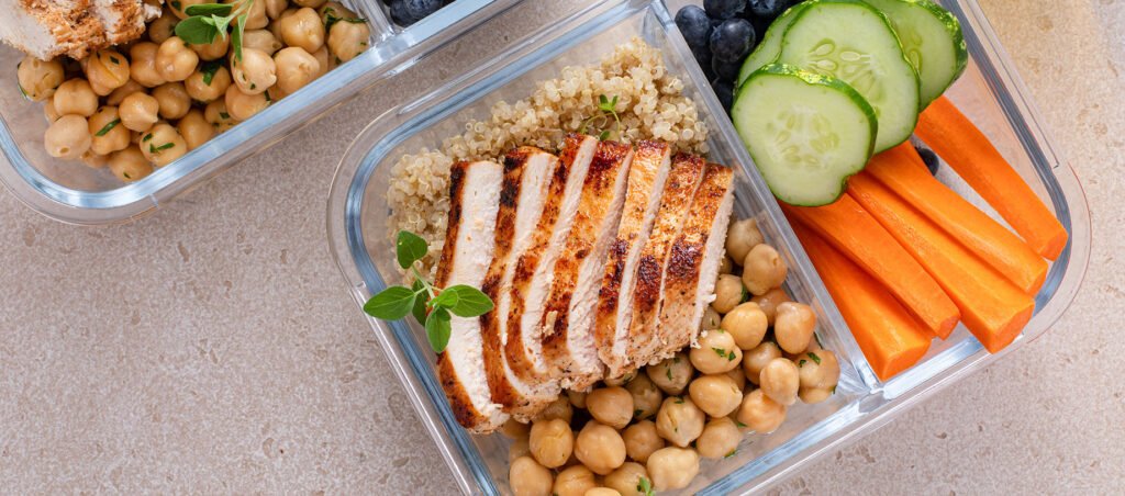 Image with healthy food like chicken, chick peas, carrots, and quinoa in meal prep boxes as part of a nutritional plan for patients taking GLP-1 medications for weight loss