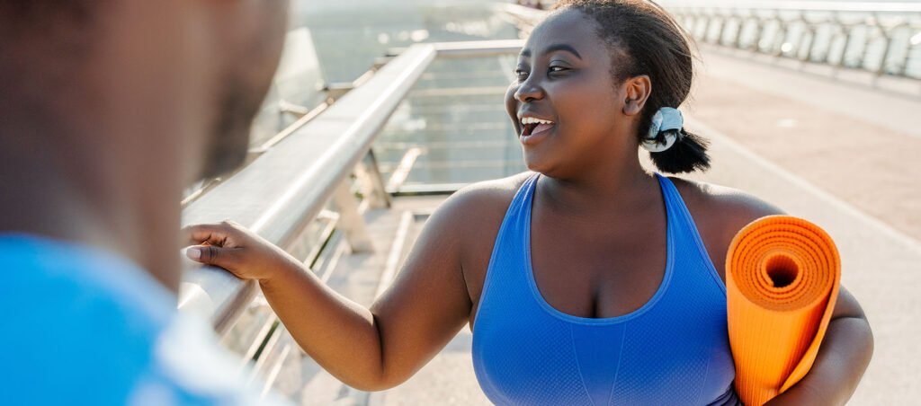 Lady on a medical weight loss journey with a GLP-1 prescription like Ozempic, Mounjaro, or Wegovy speaks with personal trainer after a workout