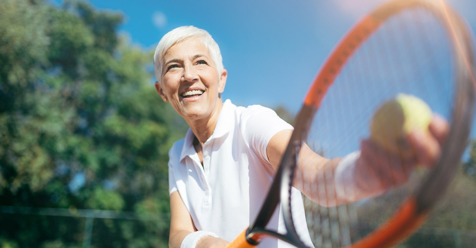 Senior lady playing tennis at a country club for holistic wellness