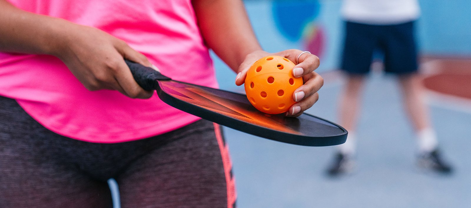 Lady holding a pickleball racket during a match at a country club with her partner.