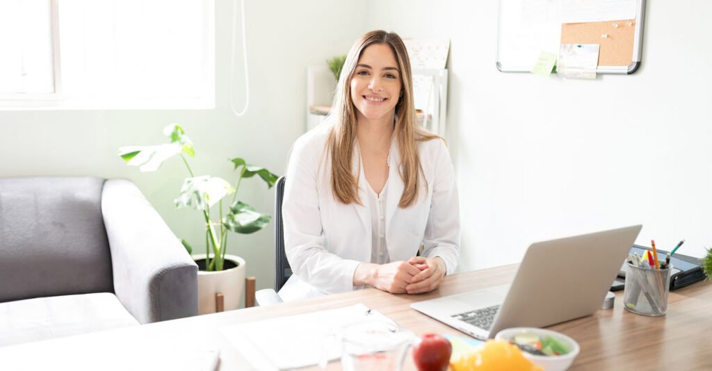 Dietitian sitting at desk in medical office after consult to help patient with nutrition and mindset on their weight loss journey with GLP-1 medications.
