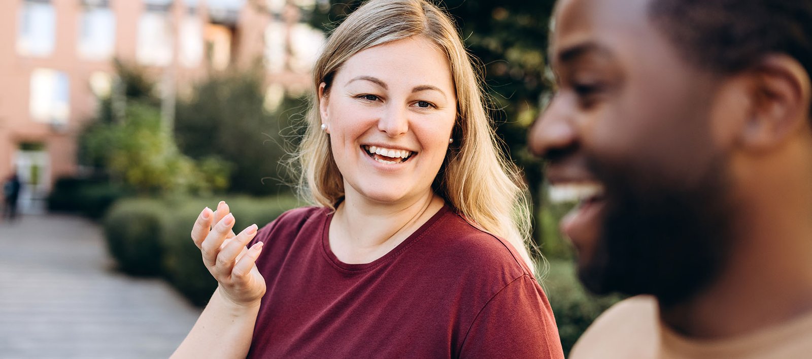 Happy young lady and man walking outside for movement and exercise on their weight management journeys.